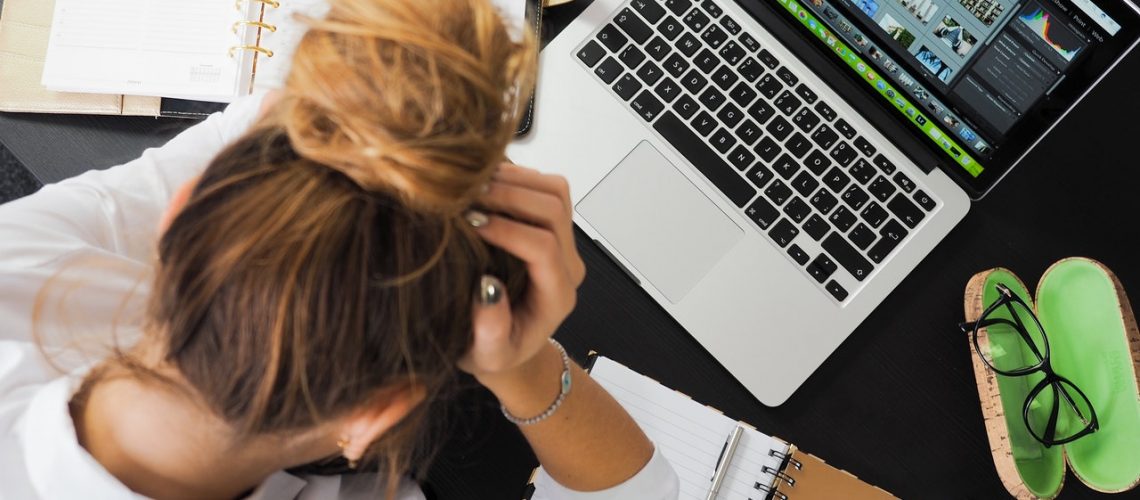 woman with head in her hands looking at laptop